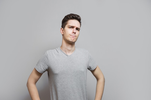 Un chico con una camiseta gris con emociones en su rostro.