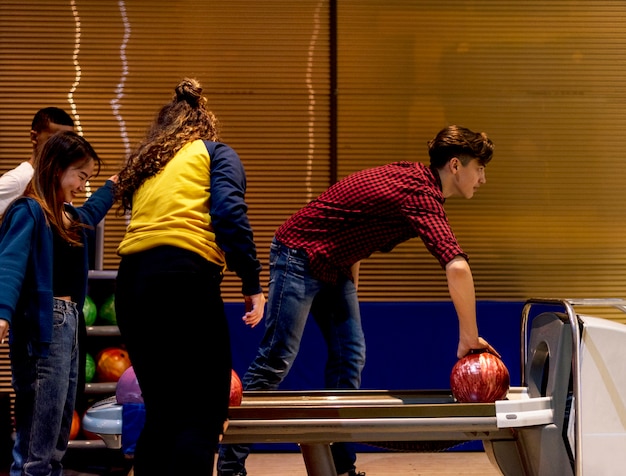 Chico caucásico recogiendo un pasatiempo bola de bolos y el concepto de ocio