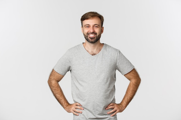 Chico caucásico sonriente en camisa gris, mirando feliz y realizado