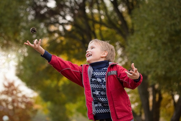 El chico de la chaqueta arroja golpes en el parque. Retrato de un niño de aspecto europeo. Emociones brillantes