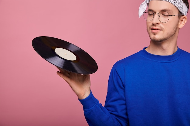 chico de chaqueta azul oscuro con pañuelo y gafas con disco de vinilo negro