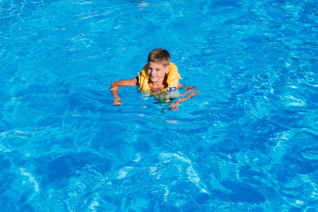 Chico en una chaqueta inflable en la piscina en verano