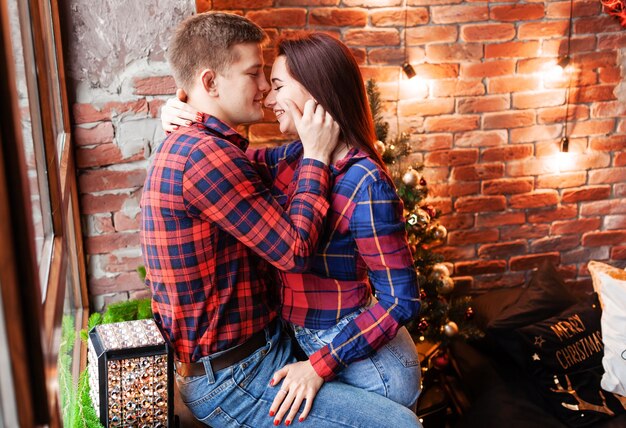 El chico y la chica se abrazan en la ventana. Una pareja enamorada se regocija en la víspera de Año Nuevo. Historia de amor de año nuevo