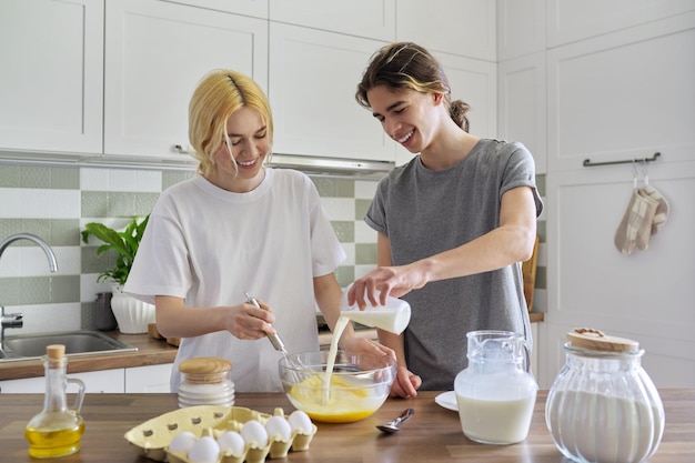 Chico y chica adolescentes cocinando panqueques en la cocina juntos