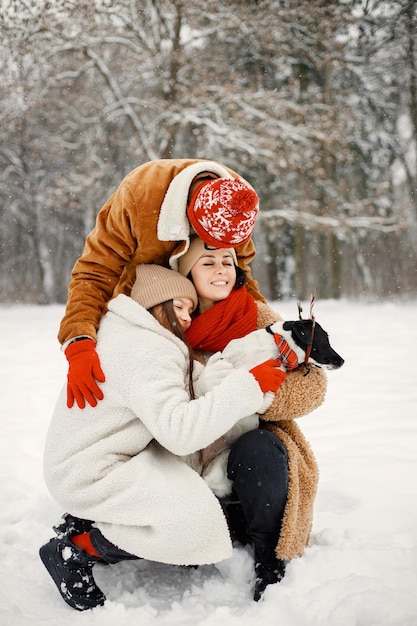 Chico y chica adolescentes con su lindo perro negro de pie en el parque de invierno