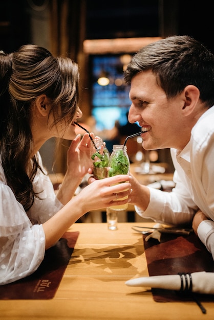 Foto chico y una chica almuerzan en un café y beben cócteles