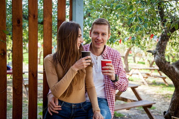 Un chico y una chica beben café en el parque en la terraza de un café