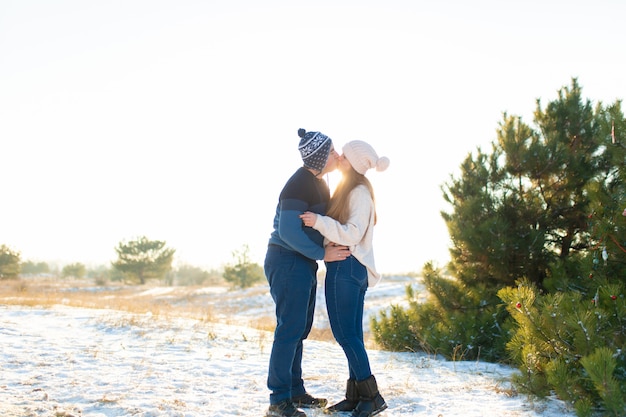 El chico con la chica beso en el invierno en el bosque