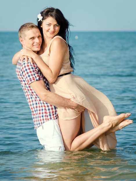 Un chico y una chica caminan por la orilla del mar, nadan en el agua.