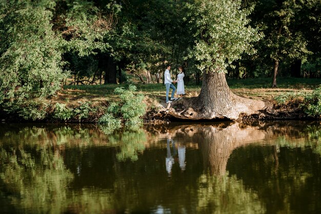 Chico y chica caminan por los senderos de un parque forestal entre árboles altos