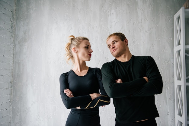 El chico y la chica en chándal. Uniforme deportivo negro. Atletas masculinos y femeninos. Cuerpo bombeado. Triatlón Entrenamiento de la mañana. Conjunto de ejercicios para el cuerpo. Clases en pareja. Entrena juntos en casa.