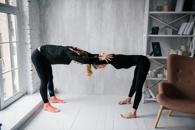 El chico y la chica en chándal. Uniforme deportivo negro. Entrenamiento de la mañana. Conjunto de ejercicios para el cuerpo. Clases en pareja. Entrena juntos en casa.