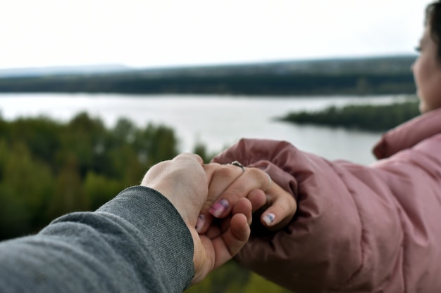 chico y chica se dan la mano en la orilla del río