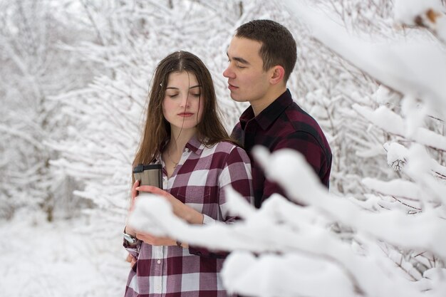 El chico y la chica descansan en el bosque de invierno Marido y mujer en la nieve Pareja joven