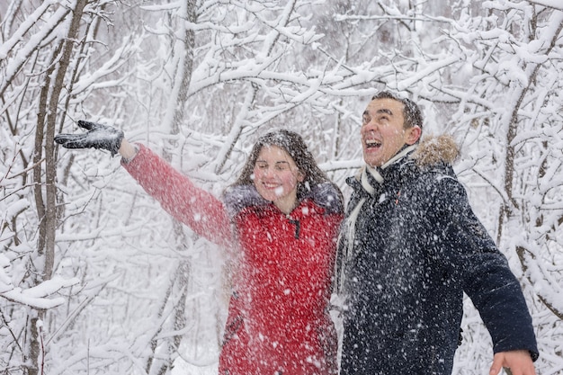 El chico y la chica descansan en el bosque de invierno. Marido y mujer en la nieve.
