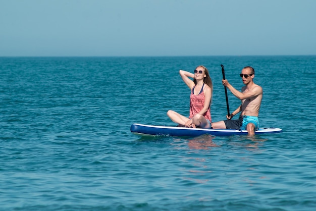 Un chico y una chica se divierten nadando en una tabla de surf en verano en el mar