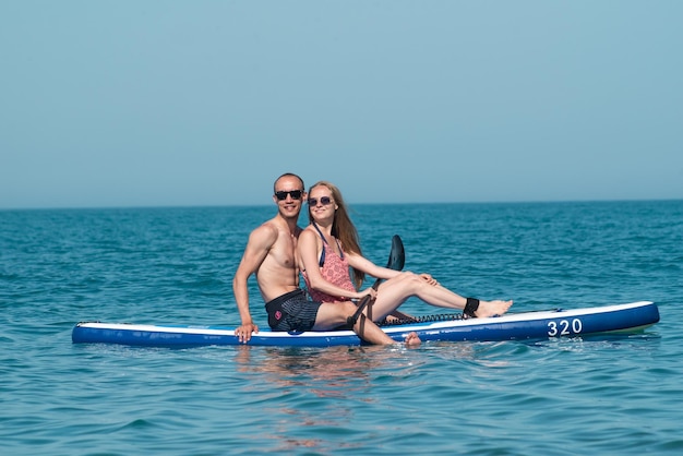 Un chico y una chica se divierten nadando en una tabla de surf en verano en el mar