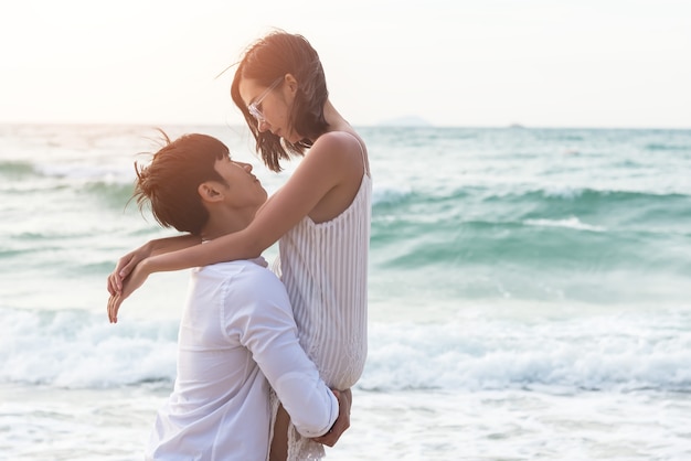 Un chico con una chica en la espalda, en la playa, al aire libre