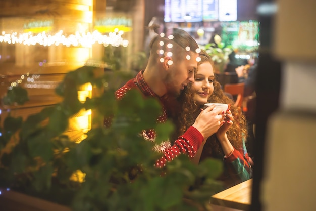 Un chico y una chica están sentados en un café junto a la ventana.