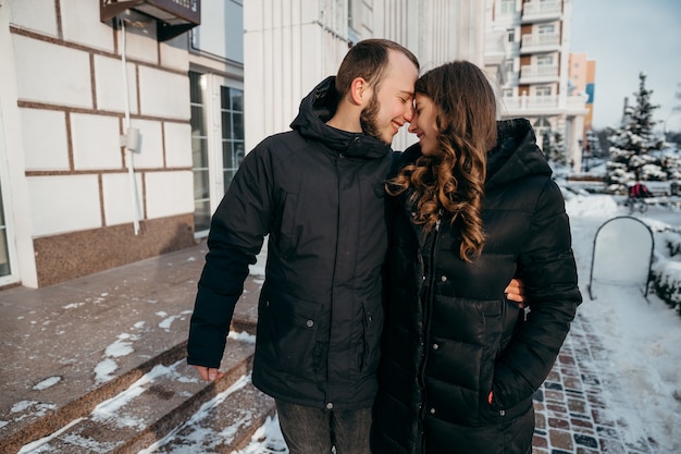 Un chico y una chica felices caminan por la ciudad cubierta de nieve y se sonríen tiernamente. Foto de alta calidad