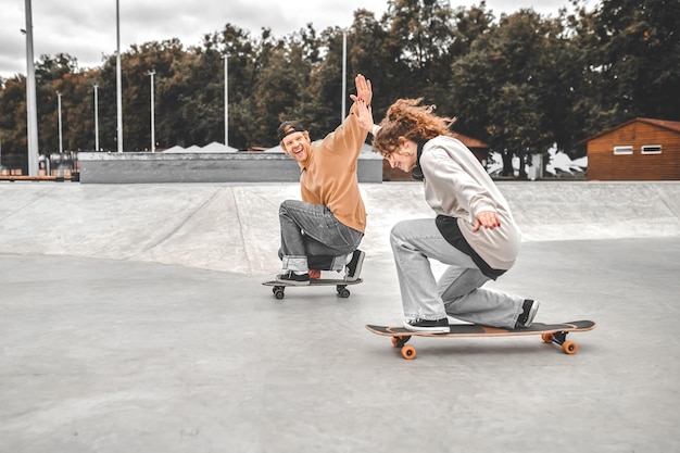 Chico y chica en patinetas extendiéndose el uno al otro