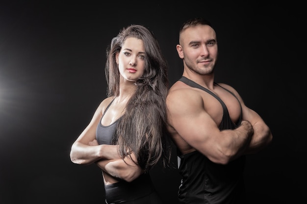 Chico y chica posando para el fitness familiar en un fondo negro