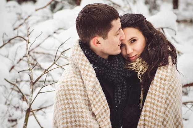 Un chico y una chica con ropa de abrigo y bufandas en un paseo por el bosque nevado y en el campo.