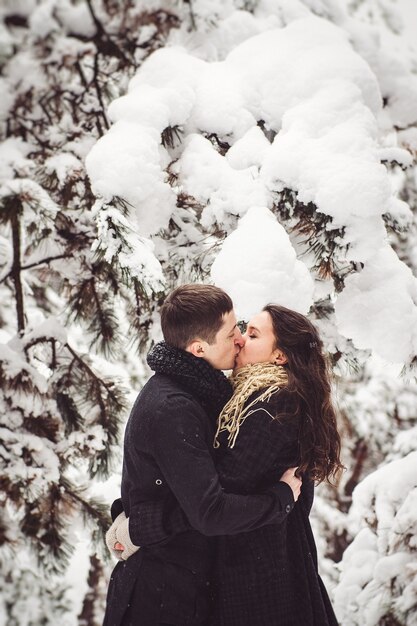 Un chico y una chica con ropa de abrigo y bufandas en un paseo por el bosque nevado y en el campo.