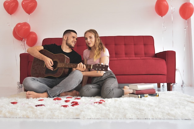 Chico chica tocando la guitarra en la habitación romántica felicidad en el amor el día de San Valentín