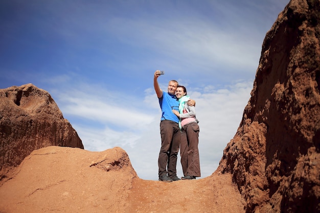 Un chico y una chica se toman una selfie mientras están en la cima de la montaña con el fondo del cielo.