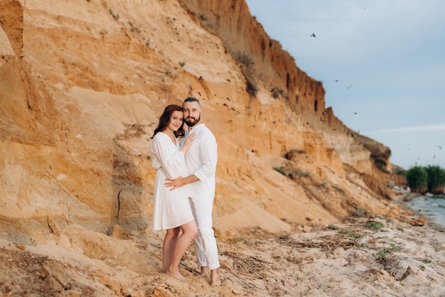 Un chico con una chica vestida de blanco a la orilla del mar.