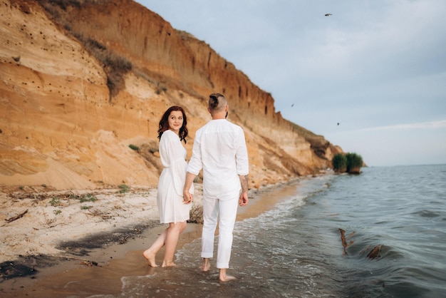 Un chico con una chica vestida de blanco a la orilla del mar.