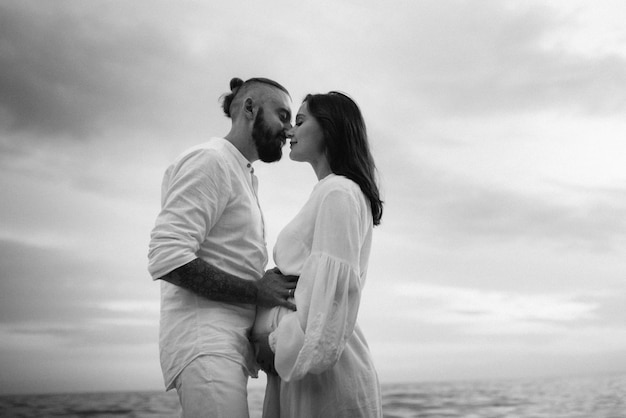 Un chico con una chica vestida de blanco a la orilla del mar.