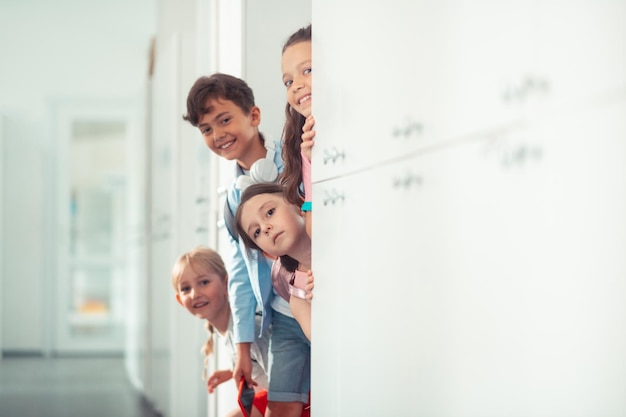 Chico y chicas sonriendo mientras están parados cerca de los casilleros en las vacaciones escolares