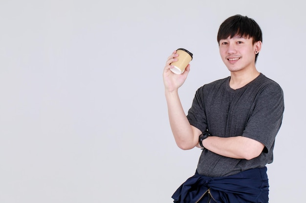 Chico chino joven inteligente en chaqueta de uniforme de servicio sosteniendo una taza de café