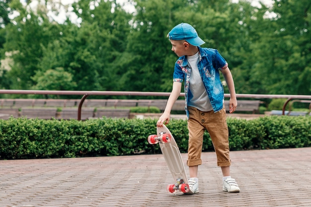 Foto un chico de ciudad pequeña y patineta. un chico joven está montando en una patineta parka