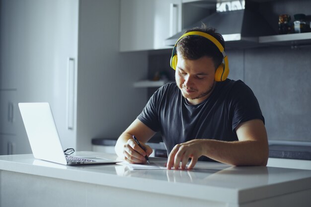 Chico concentrado con auriculares escuchando música mientras planifica la jornada laboral