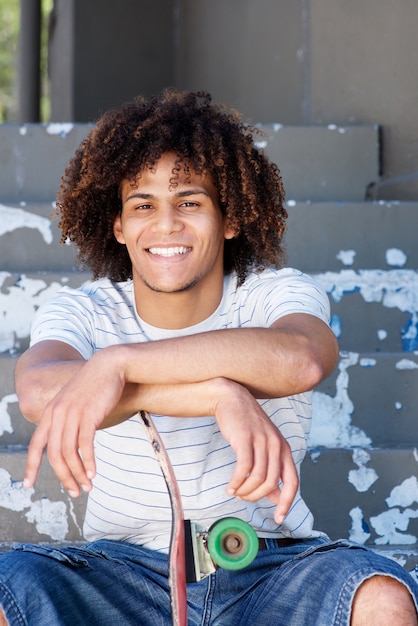 Foto chico cool sonriente sentado afuera con patín