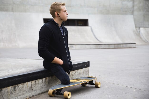 Chico discapacitado joven y motivado con un longboard en el skatepark