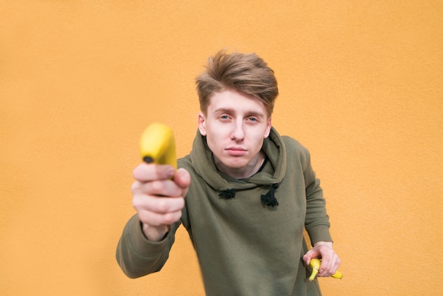 Un chico divertido sostiene un plátano en sus brazos. Centrarse en un hombre joven.