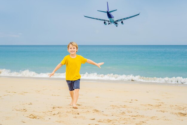 Chico diviértete en la playa viendo los aviones aterrizando Viajando en un avión con el concepto de niños