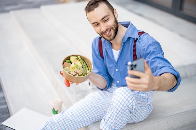 Chico elegante come comida saludable para llevar en el trabajo al aire libre