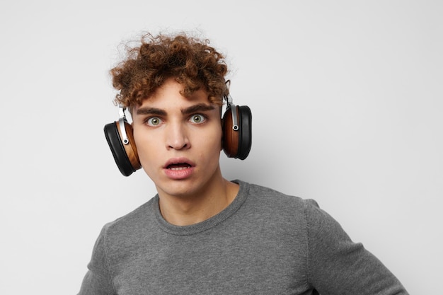 Chico elegante escuchando música en auriculares emociones fondo claro