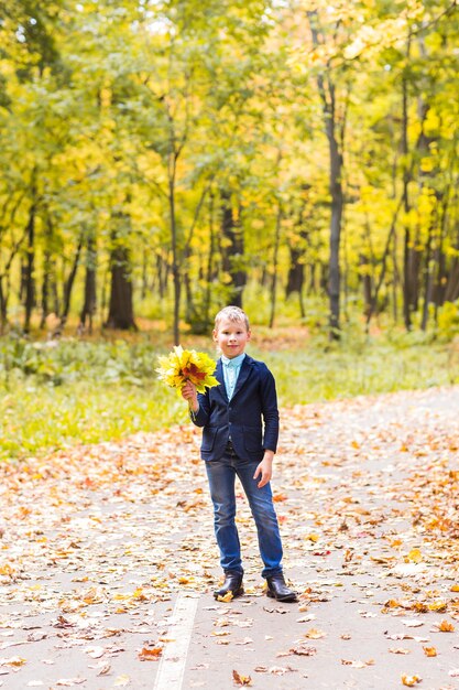 Chico elegante posando en el parque otoño con hojas