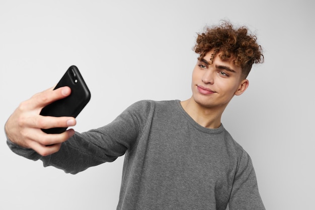 Chico elegante con un teléfono en la mano comunicación fondo aislado