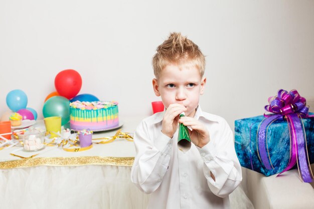 Chico encantador está celebrando la fiesta de cumpleaños con tarta y regalos