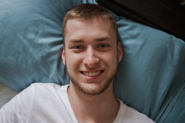 Un chico está acostado en la cama y sonriendo.