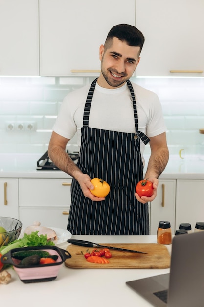 El chico está cocinando en su cocina. Piensa qué cocinar con verduras.