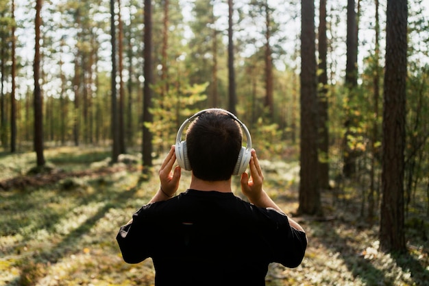 El chico está escuchando un audiolibro Música tranquila y relajante con auriculares con la espalda mirando