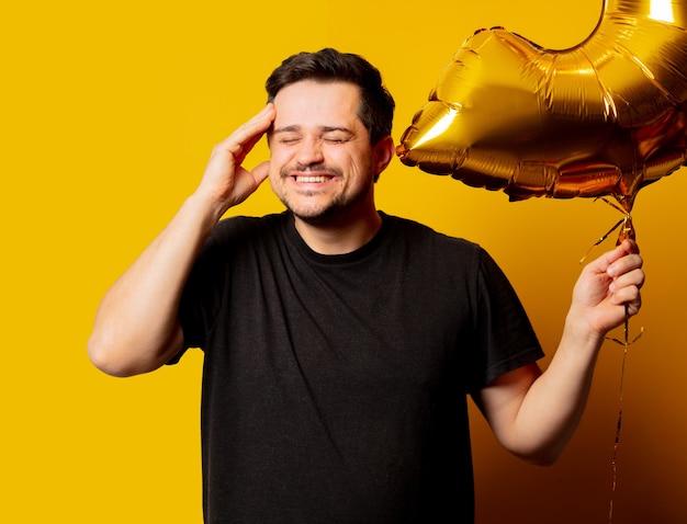 Foto chico de estilo en camiseta negra con globo dorado